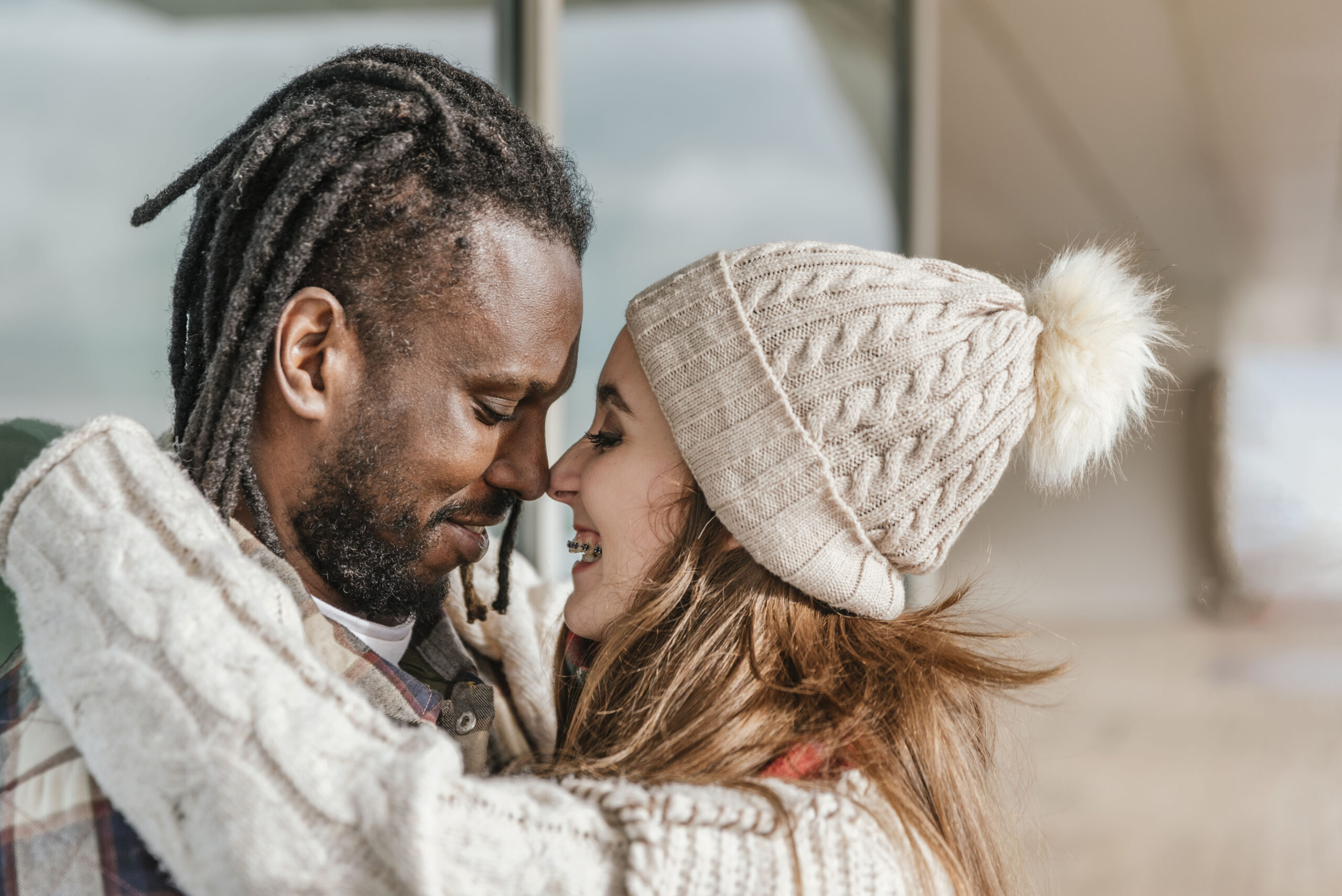 close up side view of smiling multiracial couple touching with noses outdoors