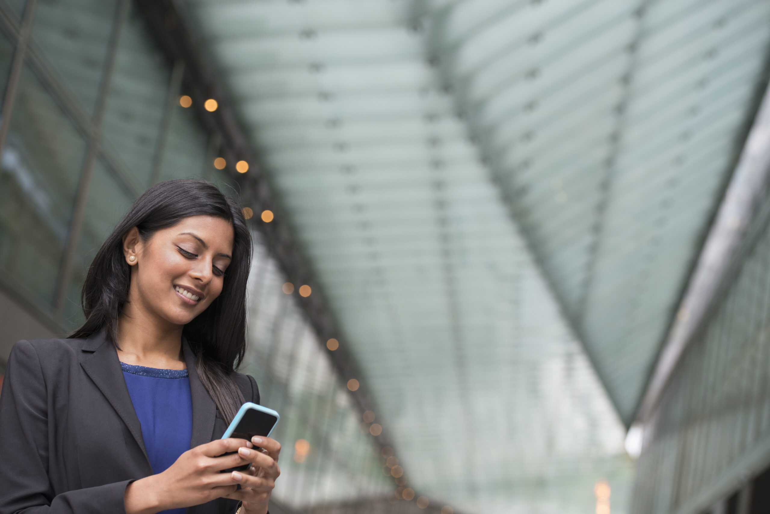 Business people out and about in the city. A young woman in a blue dress and grey jacket.